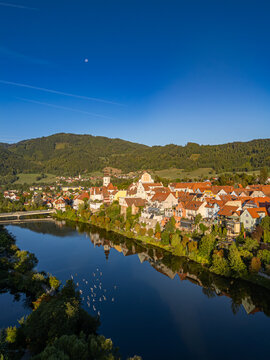 Wide panoramic aerial view of the historic town of Frohnleiten, showing the Mur River, road bridge, and parish church in Styria, Austria
