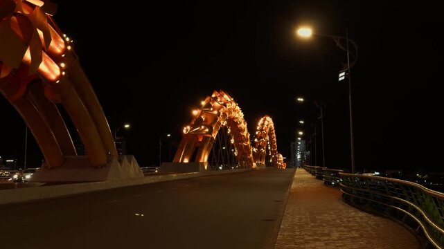 Dragon bridge in da nang illuminating the night sky, showcasing its unique architectural design and golden scale like sections, connecting both sides of the city across the han river