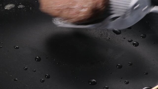 Grilled hamburger steak patty with seared crust cooking on a black griddle, camera zooms in and pans across the surface