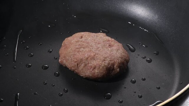 Grilled hamburger steak patty with seared crust cooking on a black griddle, camera zooms in and pans across the surface
