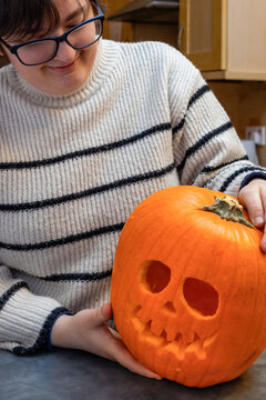 Young woman proudly showing carved Halloween jack-o-lantern skul