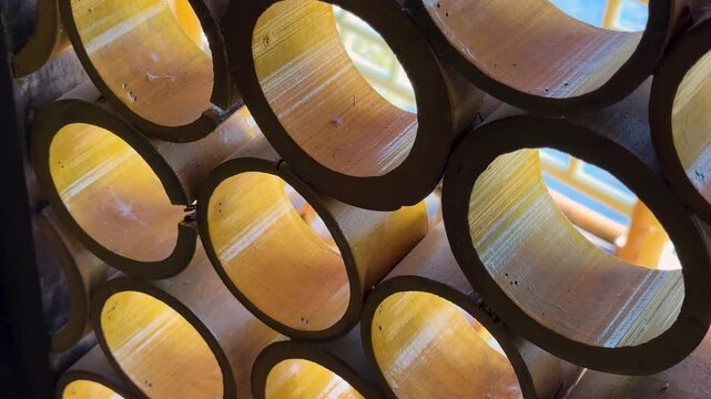 Detailed view of sunlight passing through a pattern of stacked bamboo tubes in a textured wall