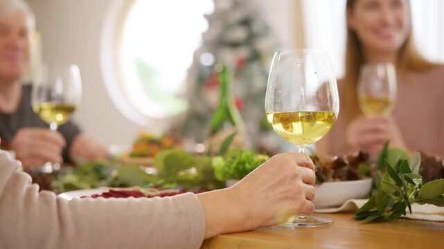 Senior parents and adult daughter enjoy Christmas dinner together at home. Happy family sharing festive holiday meal with roast chicken, salad and wine around dining table during seasonal celebration.