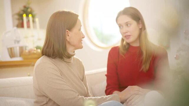 Family Christmas festive holiday celebration. Adult daughter giving gift to senior mother at home. Happy Caucasian women sharing special moment bonding with family and seasonal tradition celebrating