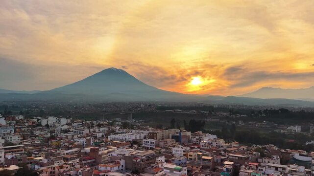 Aerial drone view of the city spread below the cone of the Misti volcano in warm sunset light, Arequipa, Peru