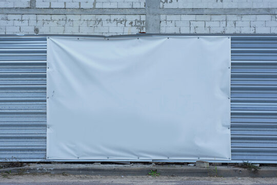 Blank white vinyl banner billboard mockup on metal fence at construction site. Large empty canvas for outdoor advertising mockup, sign board template or commercial marketing message.