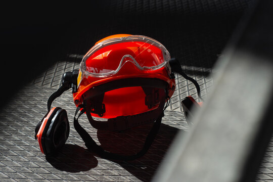 Safety hard hat with protective goggles and earmuffs on industrial metal surface. Personal protective equipment concept for construction, occupational health and safety regulations compliance.