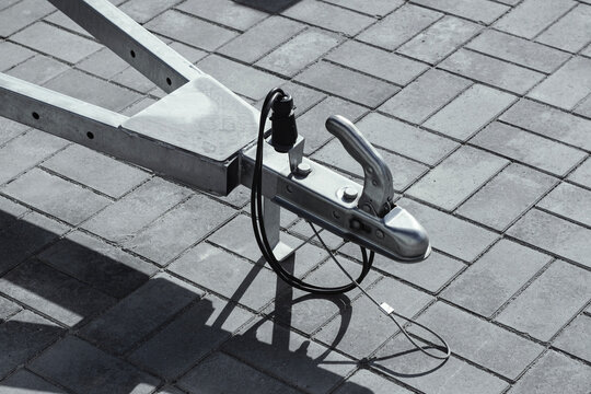 Trailer hitch coupling mechanism with safety cable and electrical plug connection. Vehicle towing equipment for cargo transport, logistics and automotive accessory technology concept.