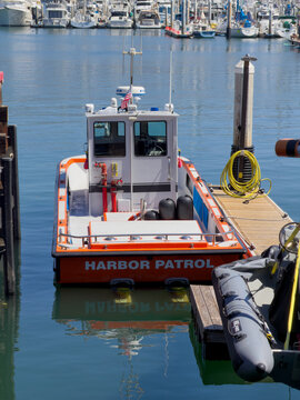 SANTA BARBARA, CA, APR 8, 2026: Close rear view of a Harbor Patrol boat's stern lettering, docked near a coiled yellow hose and inflatable tender.