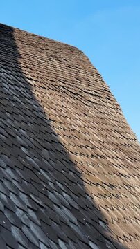 Wooden shingles on a building rooftop surface with bright sunlight and dark shadow contrast
