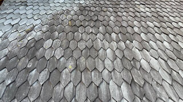 Weathered wooden shingles creating a repeating geometric pattern on an old building rooftop surface