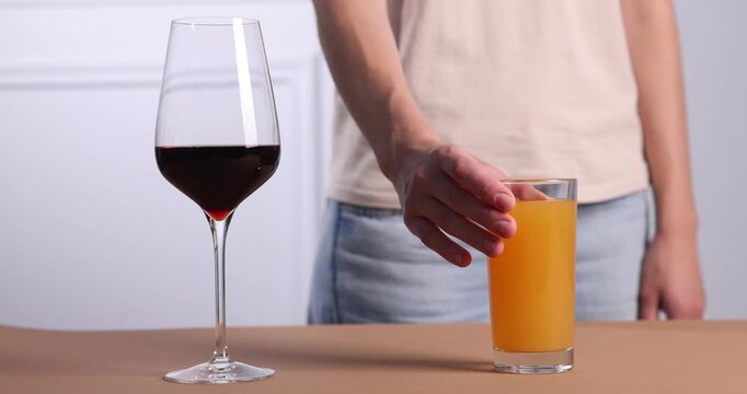 Woman choosing between wine and juice at brown table, closeup