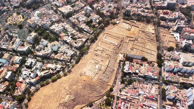 Aerial drone view of the adobe pyramid of Huaca Pucllana surrounded by city streets and buildings, Lima, Peru