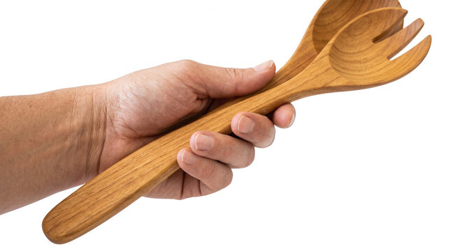 Eine Hand h&auml;lt ein Set aus h&ouml;lzernem Salatbesteck bestehend aus einem L&ouml;ffel und einer Gabel vor einem isolierten wei&szlig;en Hintergrund f&uuml;r kulinarische Konzepte