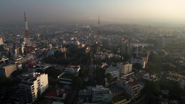 Panoramic aerial view of church on La Paz hill in Puebla during foggy sunrise with revolving drone footage around historical religious temple architecture and urban broadcasting towers
