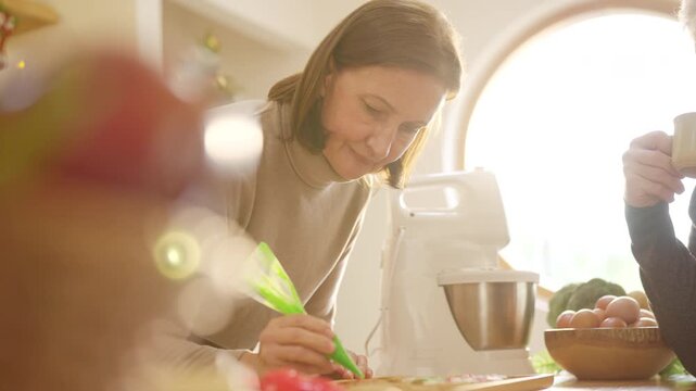 Happy family Christmas festive holiday celebration. Senior parents and adult daughter preparing and decorating holiday cookies together. Caucasian family enjoy festive treats in the kitchen.