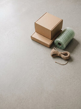 cardboard packaging boxes bubble wrap roll and jute twine on gray concrete for delivery and shipping online store parcels