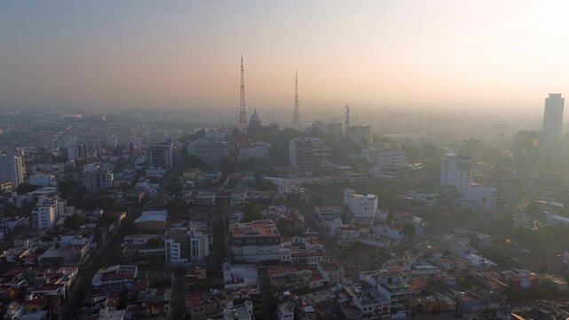 Puebla cityscape at magenta sunset with mist surrounding La Paz neighborhood and its distinctive white dome church above the urban horizon