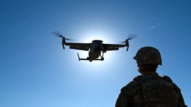 Military soldier watching osprey tiltrotor aircraft flying against bright sun in clear blue sky