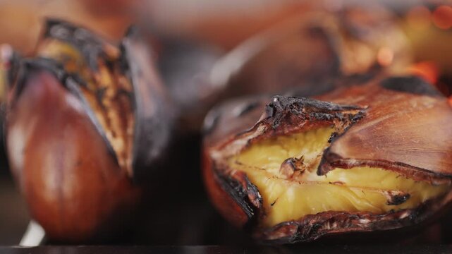 Grilled Fresh chestnut, supermarket food, grill Oven roasted chestnuts with sliced peel on wooden board, spanish traditional winter dish.