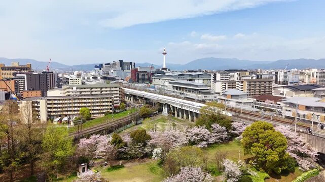 Aerial drone view of a white bullet train on the elevated tracks with the city and Kyoto Tower behind, Kyoto, Japan