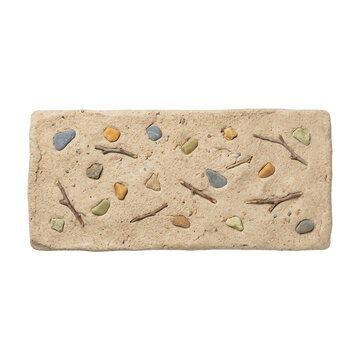 Un mattone rettangolare in argilla naturale decorato con piccoli sassi colorati e rametti secchi incastonati nella superficie, isolato su sfondo bianco per progetti di design e artigianato creativo.