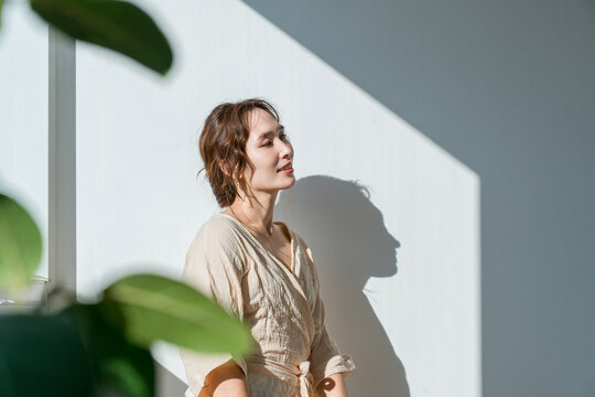 Woman Relaxing with Eyes Closed in Sunlight and Dramatic Light and Shadow