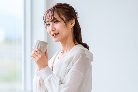 Woman in Her 40s or 50s Relaxing by the Window with a Warm Drink and Enjoying Peaceful Me Time