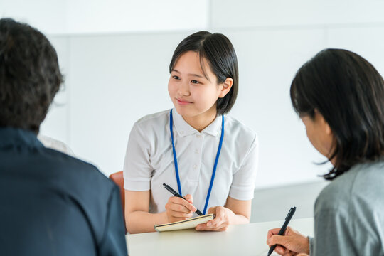 Teenage New Female Employee Taking Notes While Listening to a Senior Colleague During Workplace Training