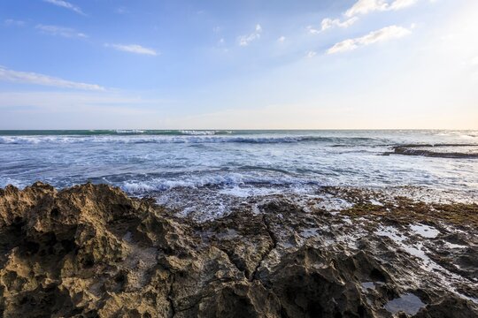 Rugged Rocky Shore and Waves Under a Bright Sky