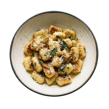 Domowe włoskie gnocchi z masłem szałwiowym i tartym parmezanem podane w ceramicznej misce na białym tle, widok z g&oacute;ry na pyszne ziemniaczane kluseczki z chrupiącą sk&oacute;rką i aromatycznymi ziołami