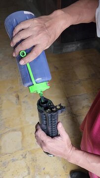 Technician refillng laser printer toner cartridge with blue powder