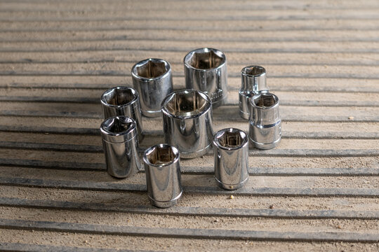 Socket wrench set arranged on surface, in metallic background, with socket wrenches, from a top down perspective, with silver, gray accents, and neutral mood, with nearby objects.