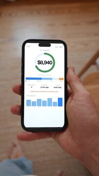 An open banking app pulls four bank accounts into a single overview with the total balance. Point of view shot in vertical format with the phone held in the hand.