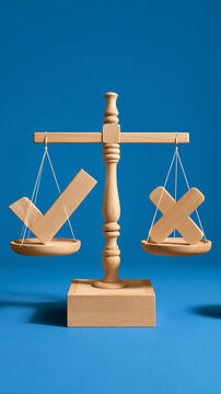 Scales of Justice: A wooden scale with a checkmark on one side and an 'X' on the other, symbolizing choice and decision-making, set against a vibrant blue background.
