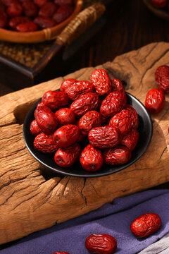 Fresh organic dried red dates in a black ceramic bowl on rustic wood