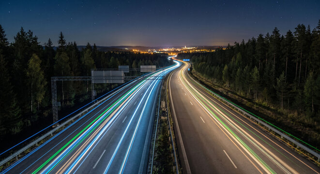 Long exposure light trails of traffic on a curved highway leading to the city skyline at night, Night traffic on a busy freeway with red and white blurred light streaks and cityscape.
