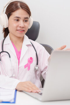 Professional doctor using laptop for telehealth, telemedical, online consultation and video meeting about Breast Cancer Awareness month, World Cancer Day and Pink October in hospital office concept