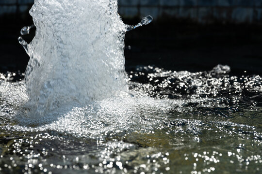 a close-up, high-speed shot of a water fountain shooting upward and splashing into a pool. summer energy background banner.