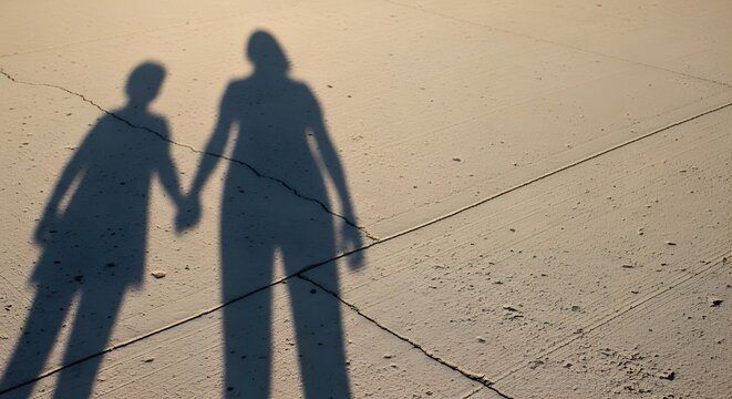 Long Shadows of Mother and Child Holding Hands on Sunlit Ground, Symbolic Family Relationship and Emotional Childhood Memory