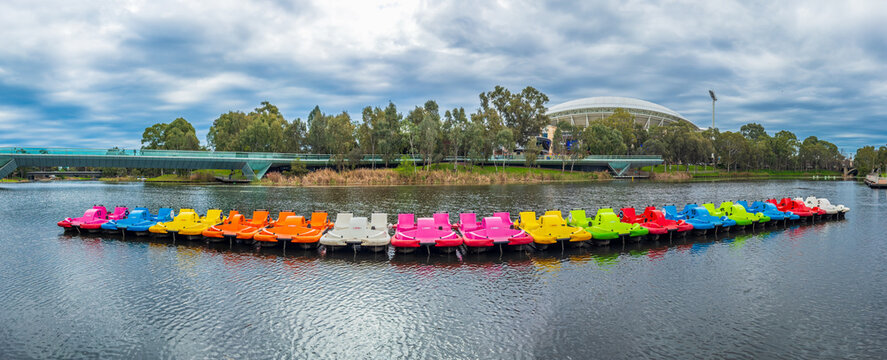 The River Torrens flows through Adelaide, South Australia, with the modern Riverbank Precinct Pedestrian Bridge leading toward the iconic Adelaide Oval stadium