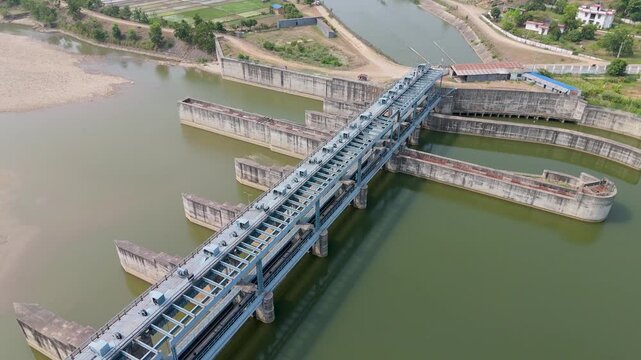 Close aerial angle overlooking the heavy concrete gates of a river barrage managing water diversion in rural Nepal