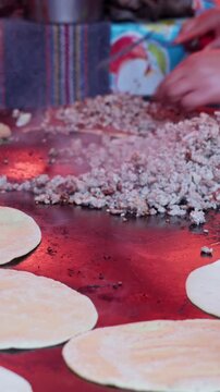 Mexican chef cooking memelas and tortillas on a hot griddle