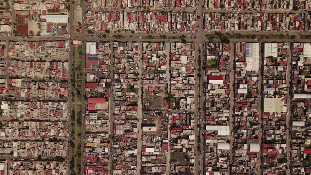 Top down aerial drone view over residential neighborhoods in Ecatepec, Mexico, showing houses, streets and urban patterns during daylight