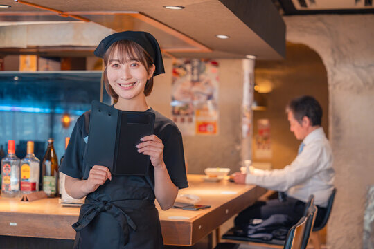 居酒屋で伝票を持つ若い女性スタッフ