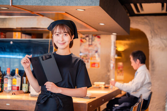 居酒屋で伝票を持つ若い女性スタッフ