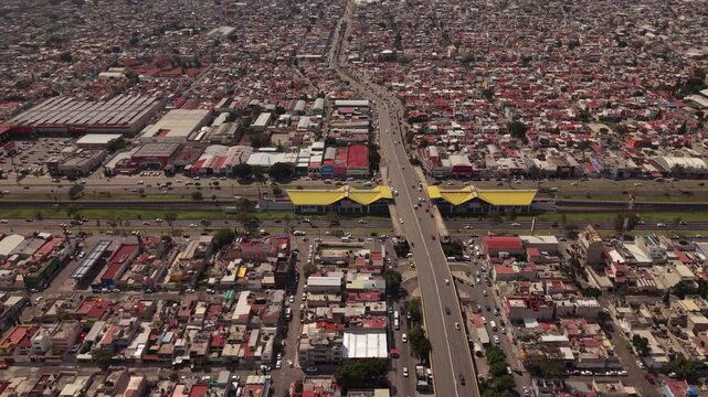 Aerial drone view of Avenida Central and Metro Line B in Ecatepec, Mexico, with moving traffic and urban surroundings during a smooth lateral flight