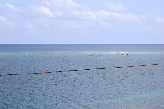 View of the turquoise Caribbean Sea in Puerto Morelos, Mexico, where local snorkeling tour boats wait near the shallow reef line.