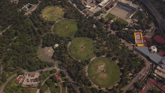 Smooth backward drone flight over Chapultepec Forest, showing dense vegetation and the surrounding urban landscape from an elevated perspective.