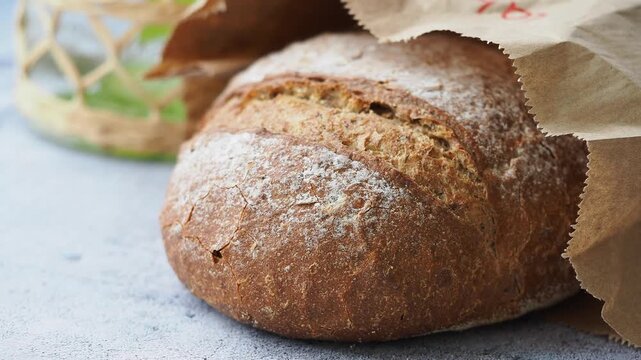 A loaf of bread sits on a table wrapped in paper